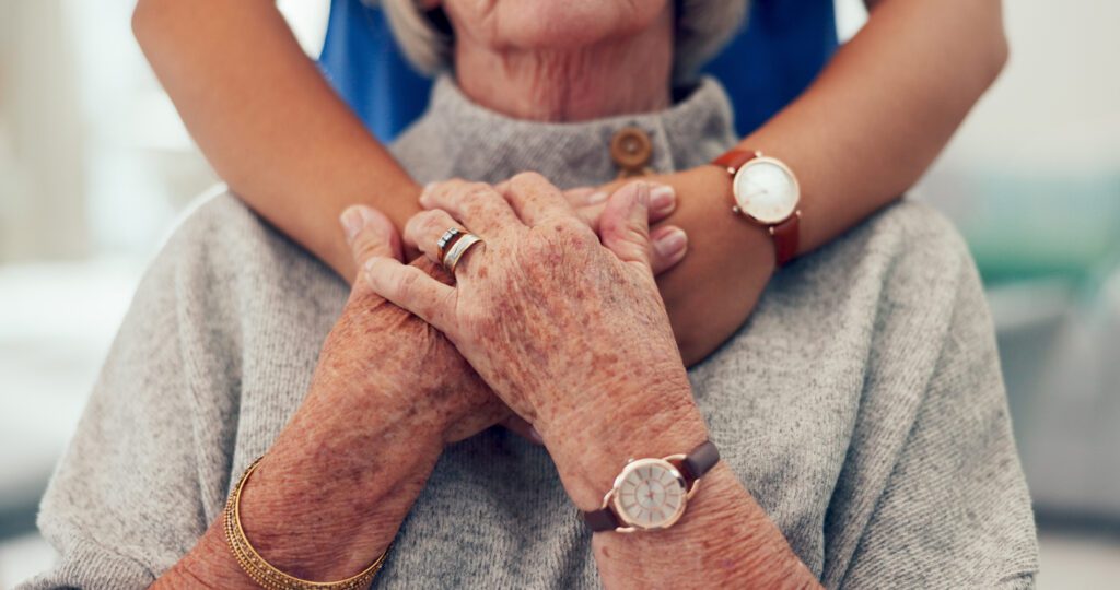 a nurses hand under an older female's hands to represent guardianship